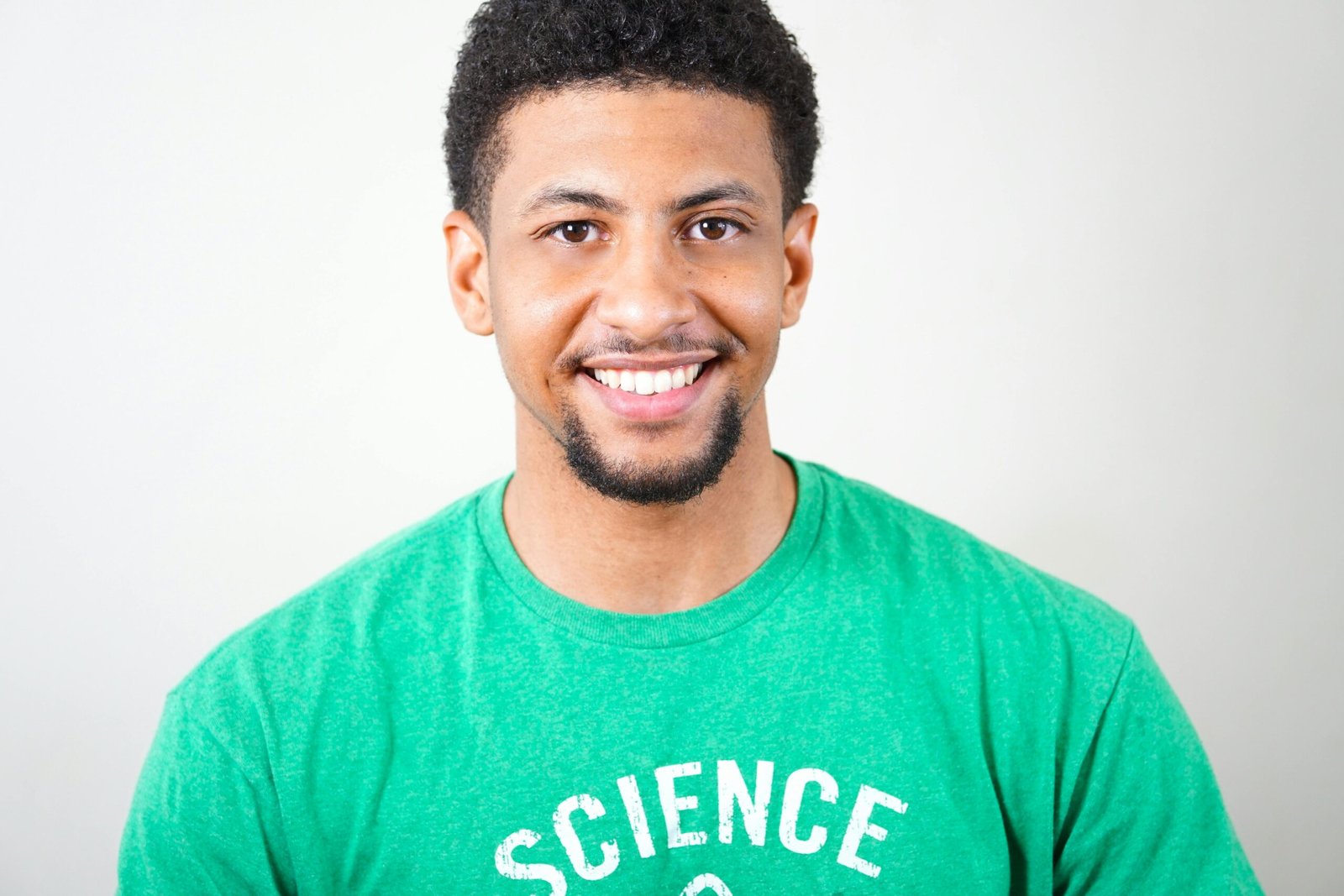 Testimonials Portrait of a smiling young man wearing a green T-shirt with science text.