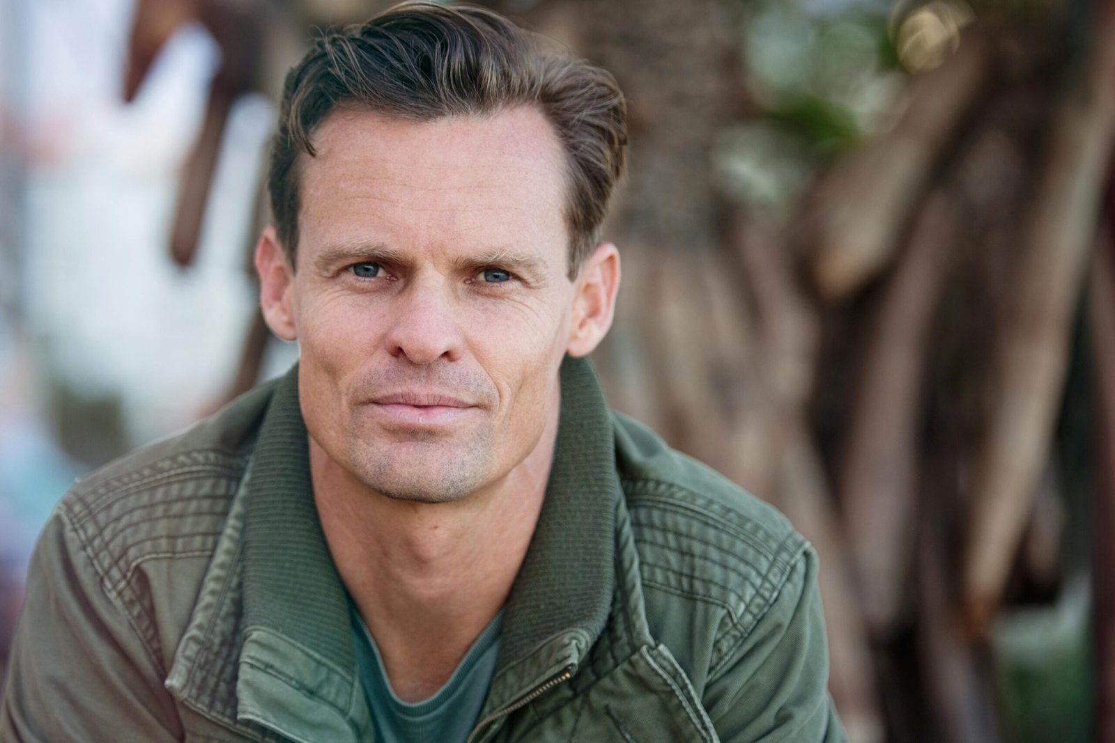 Testimonials Close-up portrait of a man wearing a casual jacket outdoors.