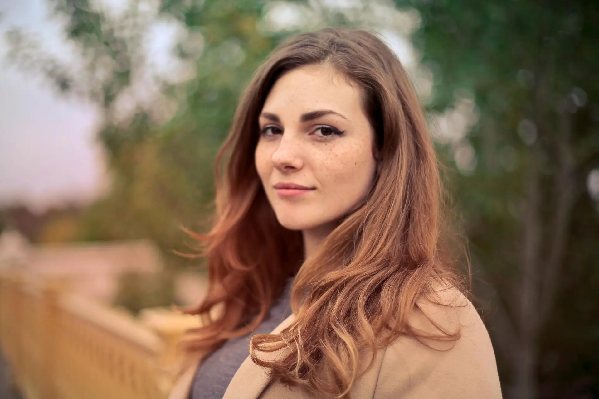 Testimonials A young woman with long hair smiles confidently for an outdoor portrait session.